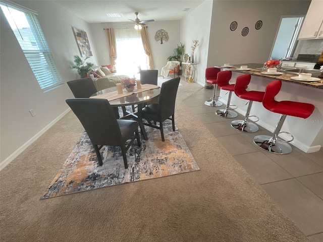 tiled dining room with ceiling fan and baseboards