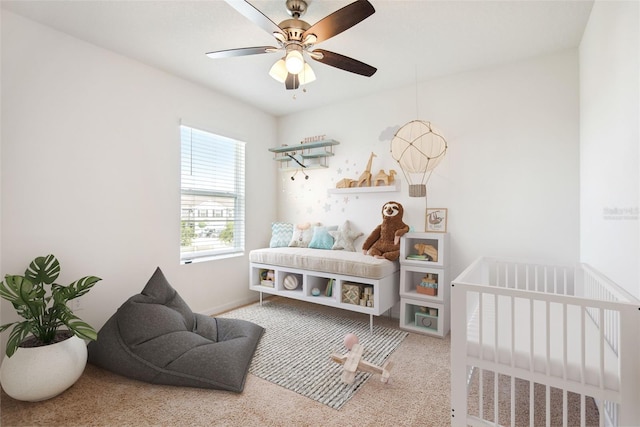 carpeted bedroom with ceiling fan and a crib