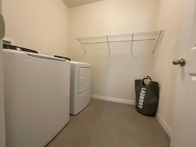 laundry area with light tile patterned floors, laundry area, independent washer and dryer, and baseboards