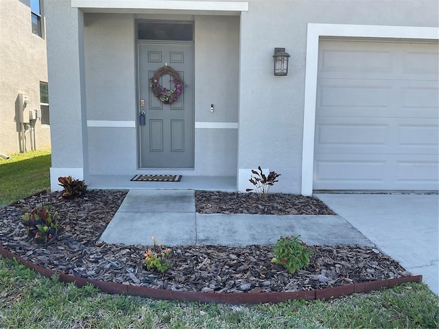 entrance to property with a garage and stucco siding
