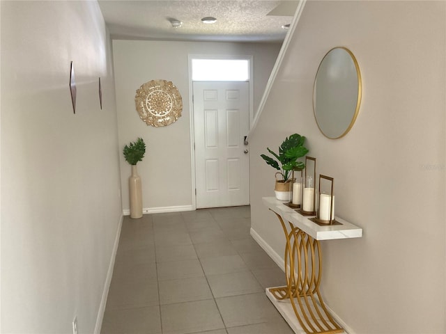 entryway with tile patterned floors, baseboards, and a textured ceiling