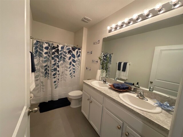 bathroom featuring visible vents, double vanity, toilet, tile patterned floors, and a sink