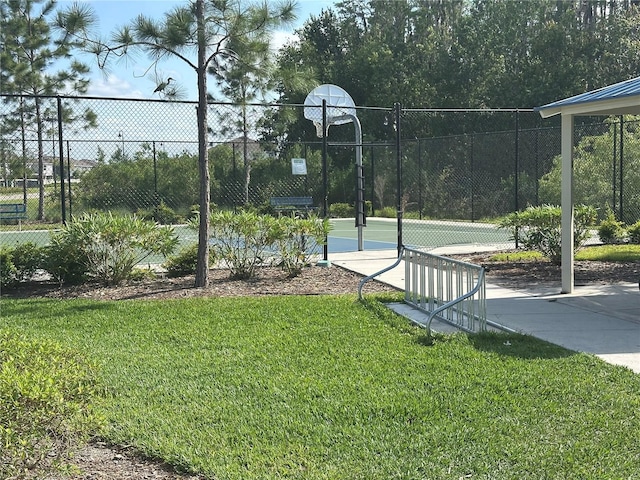 view of basketball court with a lawn, fence, and community basketball court