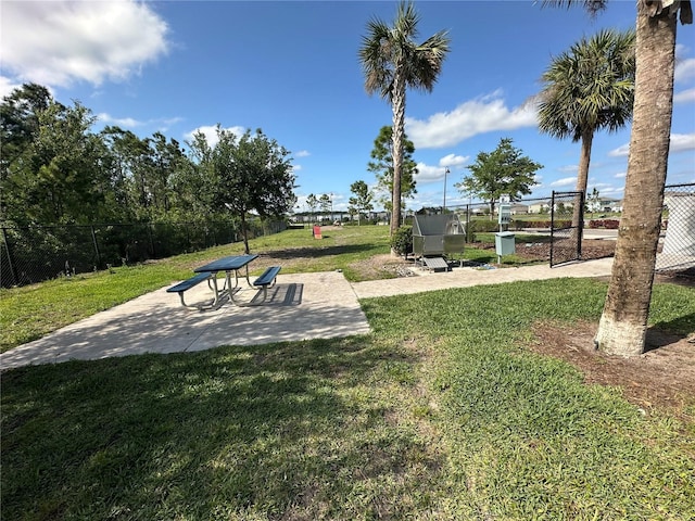 view of community with fence, a patio, and a yard