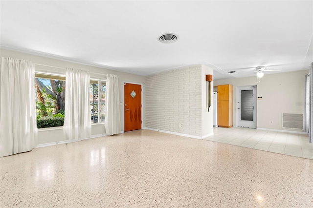 interior space with ceiling fan and brick wall