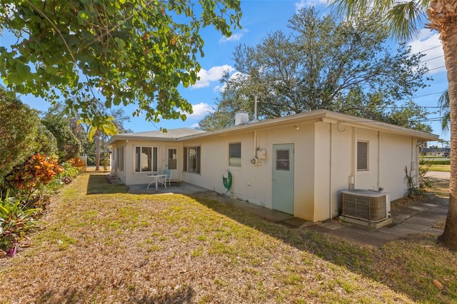 rear view of house featuring central AC unit, a yard, and a patio