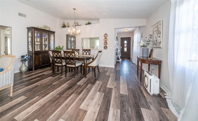 dining space with a notable chandelier, vaulted ceiling, dark hardwood / wood-style floors, and a healthy amount of sunlight