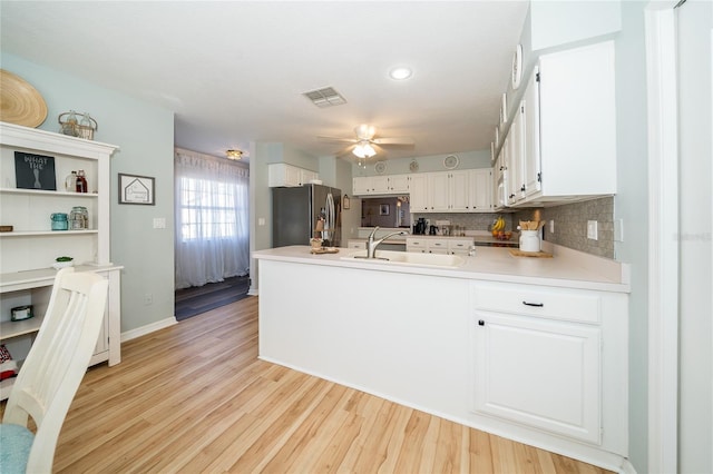 kitchen featuring sink, stainless steel fridge, light hardwood / wood-style flooring, ceiling fan, and white cabinetry