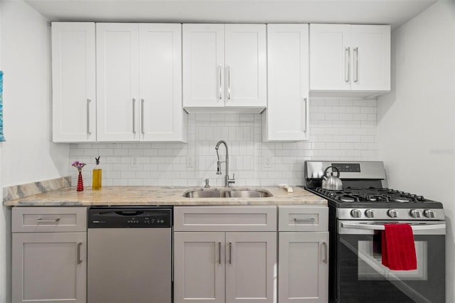 kitchen with tasteful backsplash, sink, white cabinets, and appliances with stainless steel finishes