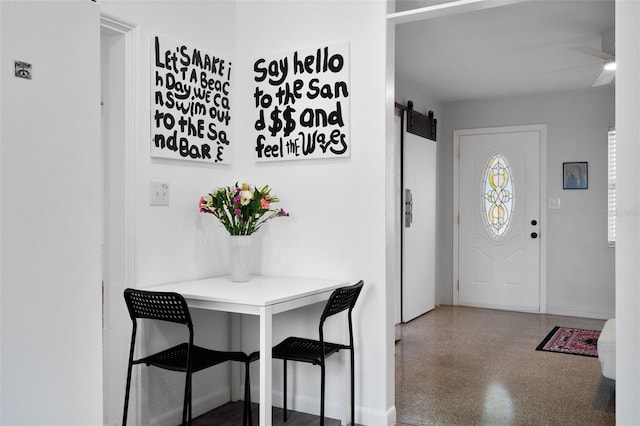 foyer entrance with ceiling fan and a barn door