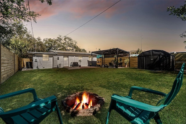 yard at dusk with cooling unit and a fire pit