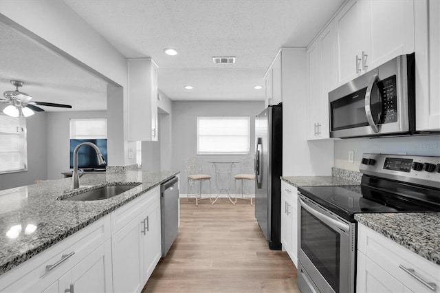 kitchen featuring light stone countertops, white cabinetry, appliances with stainless steel finishes, and sink