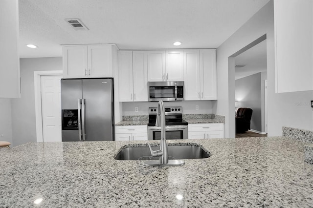 kitchen featuring light stone counters, stainless steel appliances, and white cabinets