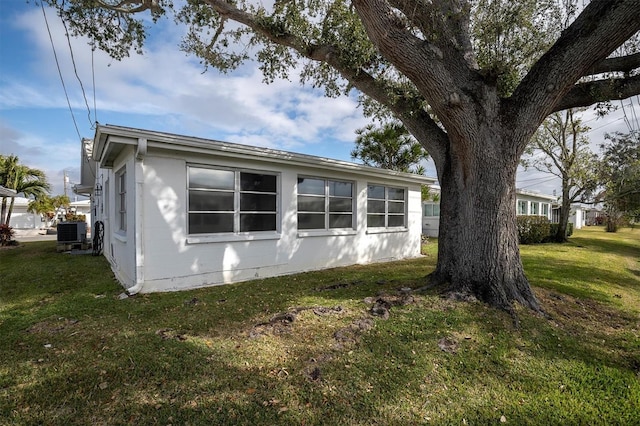 view of side of home featuring cooling unit and a lawn