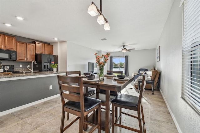 dining room with sink, light tile patterned floors, and ceiling fan