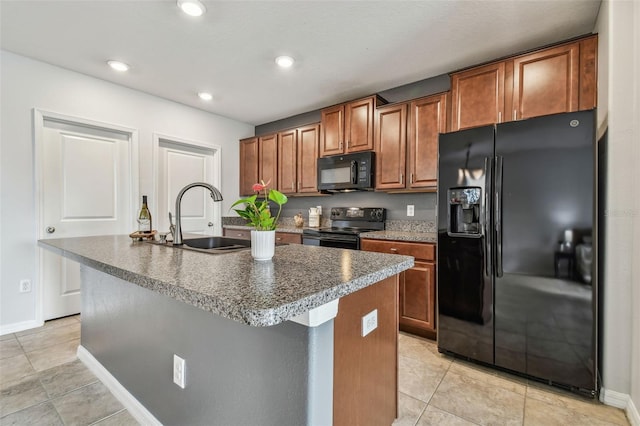 kitchen with a kitchen island with sink, sink, light tile patterned floors, and black appliances