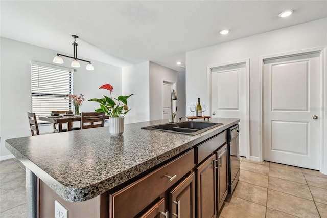 kitchen featuring light tile patterned flooring, decorative light fixtures, dishwasher, sink, and a kitchen island with sink