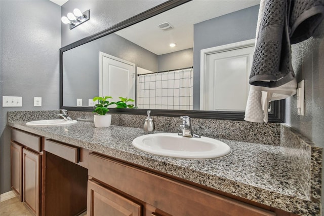 bathroom featuring double vanity, a shower with curtain, visible vents, and a sink