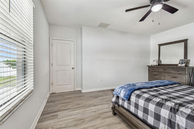 bedroom featuring light wood-style floors, visible vents, baseboards, and a ceiling fan