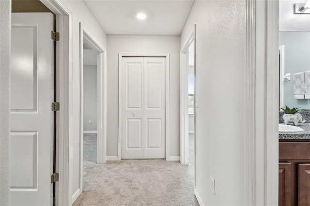 corridor featuring baseboards and light colored carpet