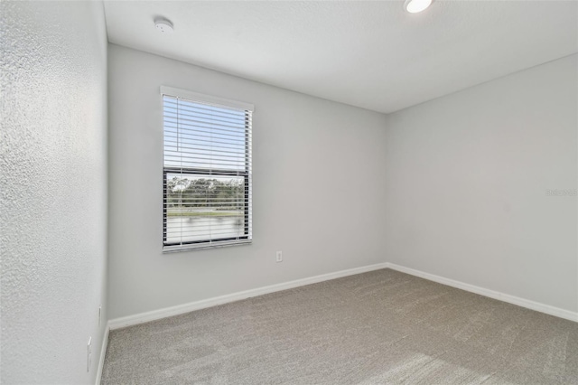 unfurnished room featuring carpet and baseboards