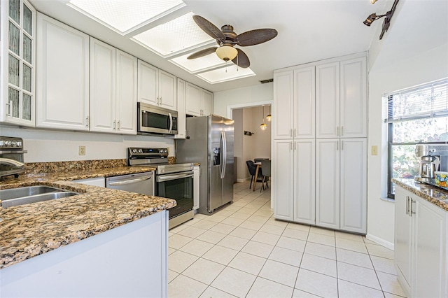 kitchen with white cabinetry, sink, stainless steel appliances, and dark stone counters