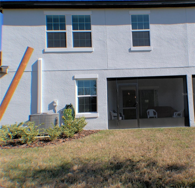 rear view of property featuring a sunroom, central AC, and a lawn