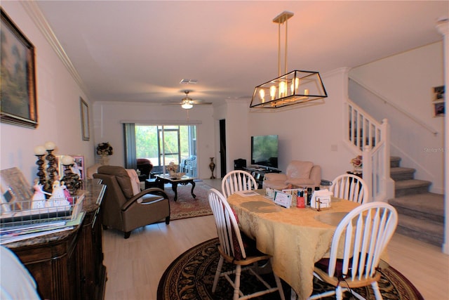 dining area featuring ceiling fan with notable chandelier, ornamental molding, and light wood-type flooring