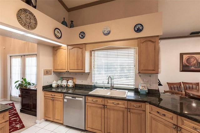 kitchen featuring sink, crown molding, dark stone countertops, stainless steel dishwasher, and a healthy amount of sunlight