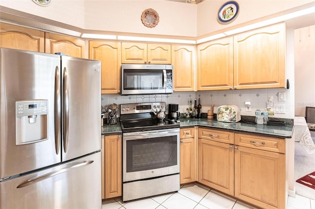 kitchen featuring backsplash, stainless steel appliances, light tile patterned flooring, and dark stone countertops