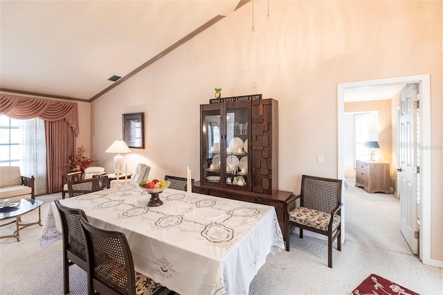 dining room featuring high vaulted ceiling, crown molding, and light colored carpet