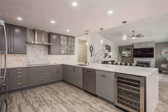 kitchen featuring decorative light fixtures, sink, beverage cooler, kitchen peninsula, and wall chimney exhaust hood