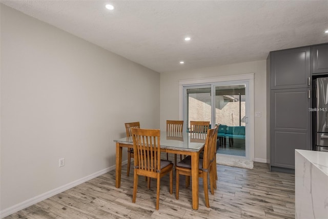 dining area with a textured ceiling and light hardwood / wood-style flooring