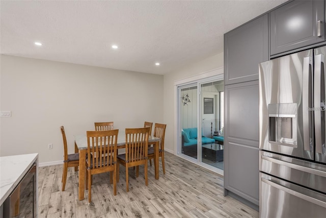 dining area featuring wine cooler, light hardwood / wood-style floors, and a textured ceiling