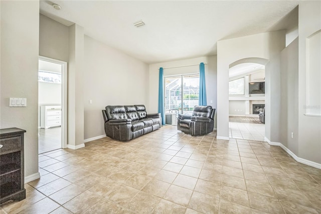 living room featuring a tiled fireplace and light tile patterned floors