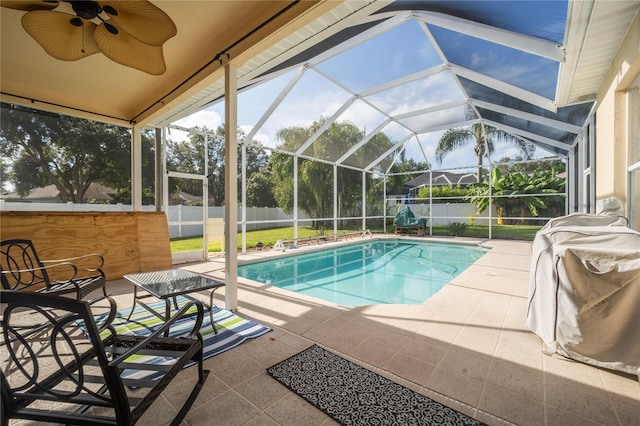 view of swimming pool with ceiling fan, glass enclosure, and a patio area