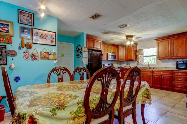 tiled dining space featuring ceiling fan and a textured ceiling