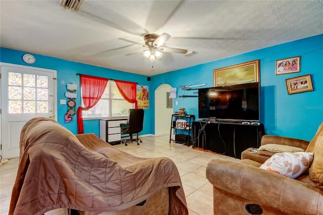 living room featuring light tile patterned flooring, ceiling fan, and a textured ceiling