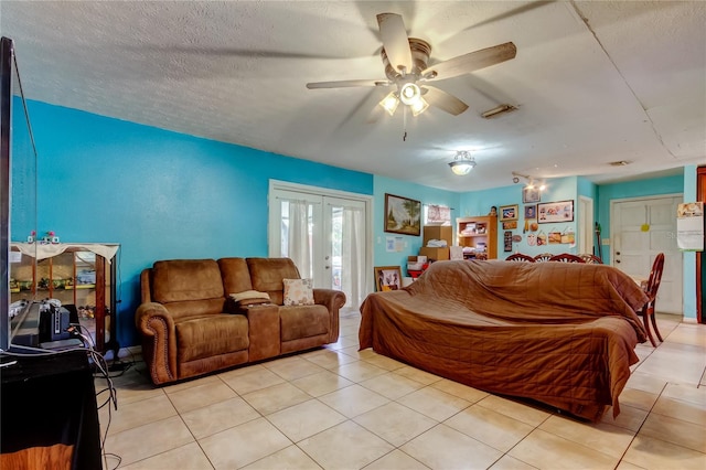 living room with ceiling fan, a textured ceiling, and light tile patterned flooring