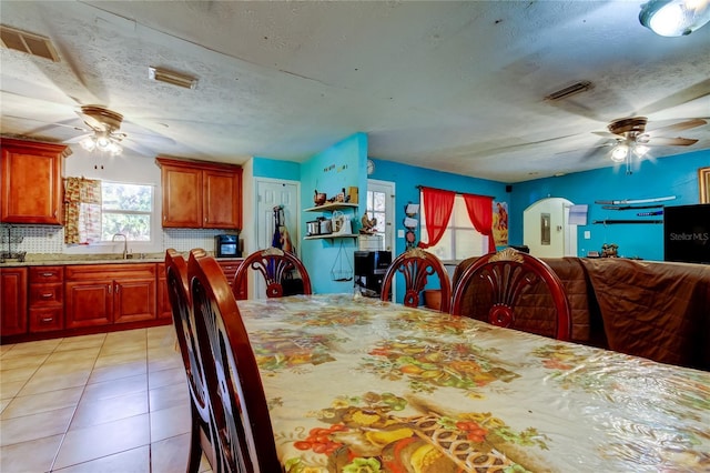 tiled dining area featuring ceiling fan, sink, and a textured ceiling