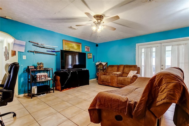 tiled living room featuring french doors, ceiling fan, and a textured ceiling