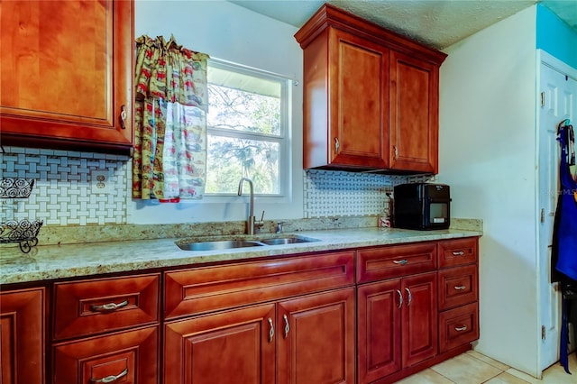 kitchen featuring light stone counters, backsplash, sink, and light tile patterned floors