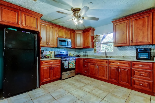 kitchen with sink, appliances with stainless steel finishes, ceiling fan, light stone countertops, and decorative backsplash