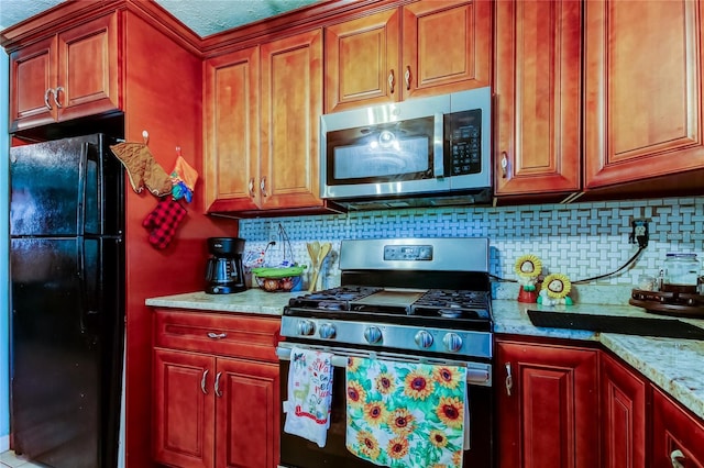 kitchen with stainless steel appliances, light stone countertops, and backsplash