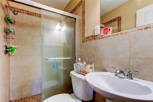 bathroom featuring a shower with shower door, sink, tile walls, decorative backsplash, and toilet