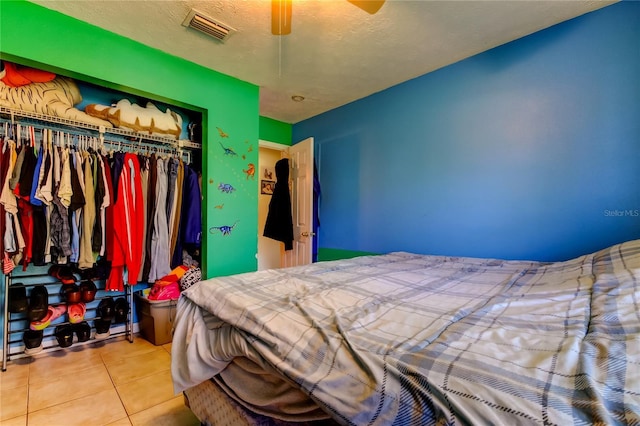 tiled bedroom featuring a textured ceiling, ceiling fan, and a closet