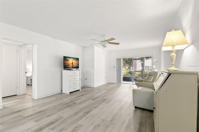 living room featuring ceiling fan, a textured ceiling, and light wood-type flooring