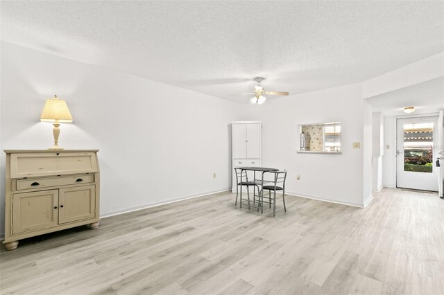 interior space with ceiling fan, a textured ceiling, and light wood-type flooring