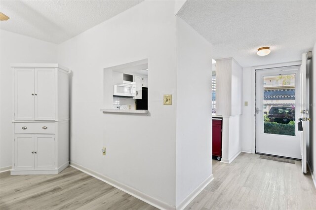 hallway featuring a textured ceiling and light hardwood / wood-style flooring