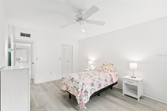 bedroom with ceiling fan, light hardwood / wood-style floors, a closet, and a textured ceiling